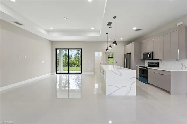 a view of a kitchen with kitchen island a large counter top space and stainless steel appliances