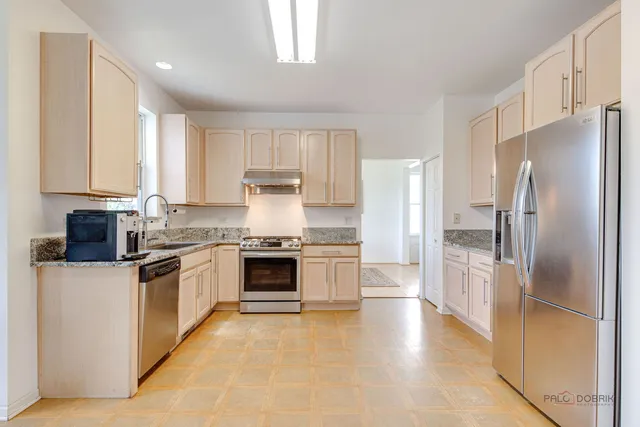 a kitchen with stainless steel appliances granite countertop a refrigerator a stove and a sink