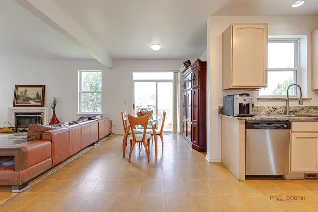 a kitchen with stainless steel appliances kitchen island granite countertop a refrigerator a stove a dining table and chairs with wooden floor