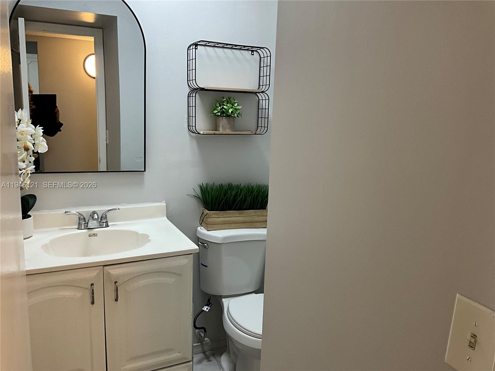 101 Berkley Road, Unit 205 Hollywood, FL 33024 - Photo 12 of 13 a bathroom with a toilet a sink and mirror