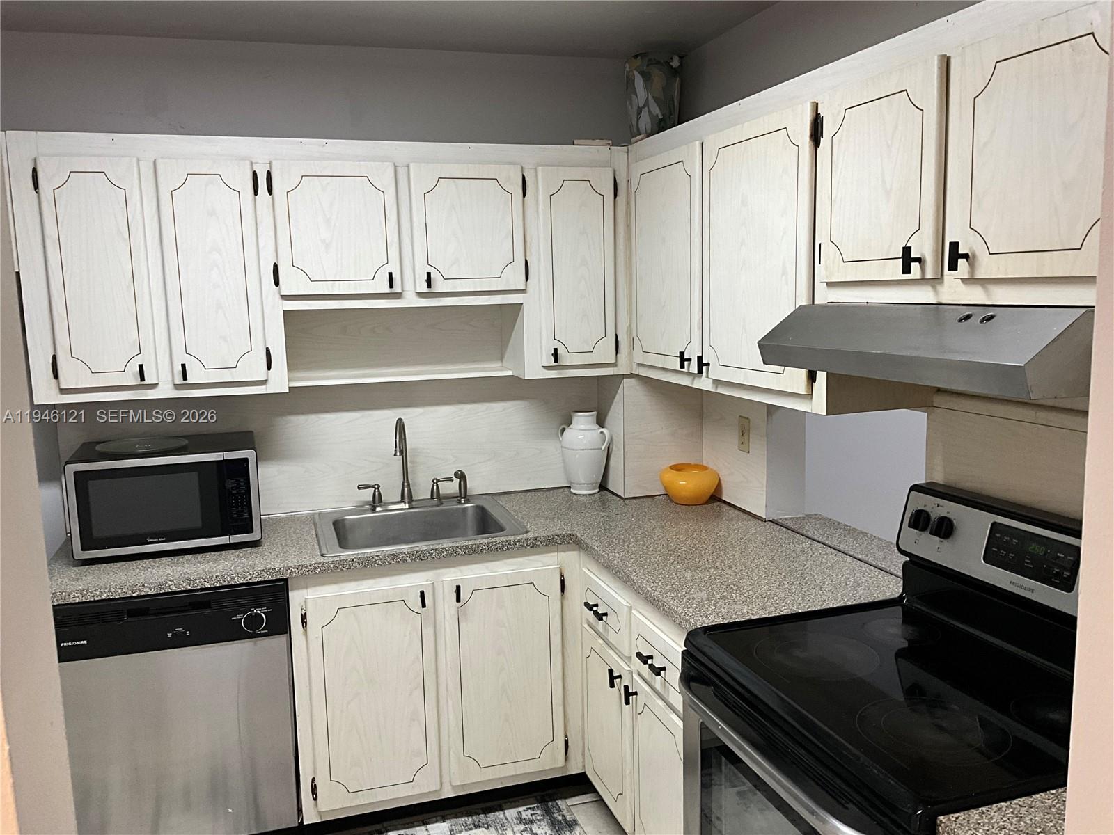 101 Berkley Road, Unit 205 Hollywood, FL 33024 - Photo 3 of 13 a kitchen with a sink stove and cabinets