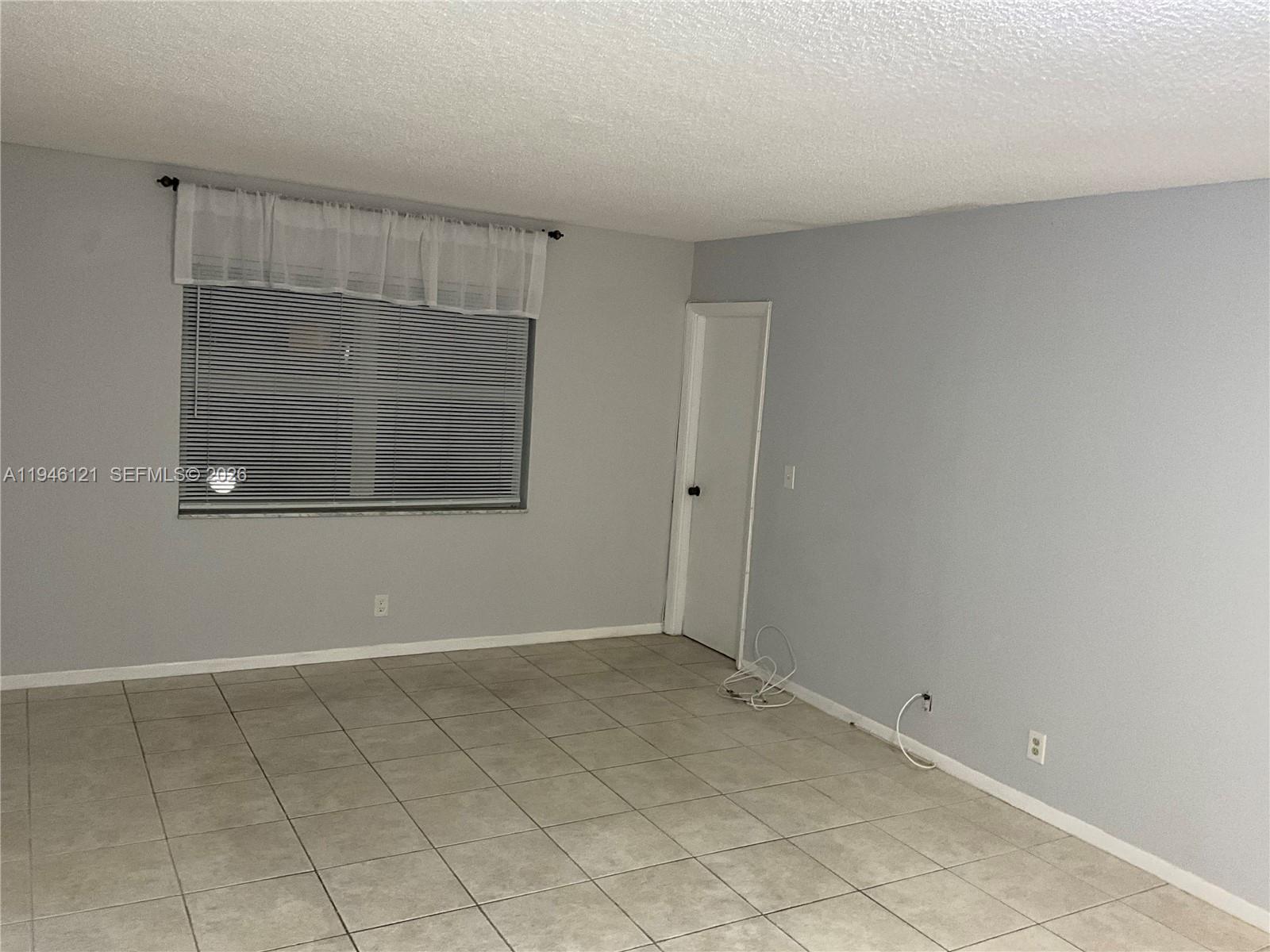 101 Berkley Road, Unit 205 Hollywood, FL 33024 - Photo 7 of 13 a view of an empty room with wooden floor and a window