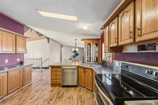 a kitchen with stainless steel appliances a stove a sink dishwasher and cabinets with wooden floor
