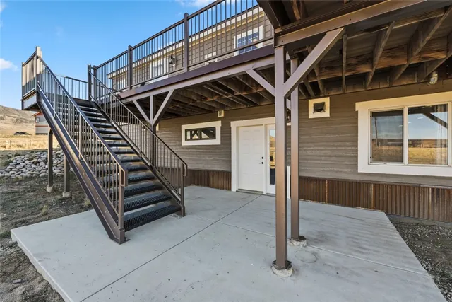 a backyard of a house with lawn chairs floor to ceiling window and ocean view