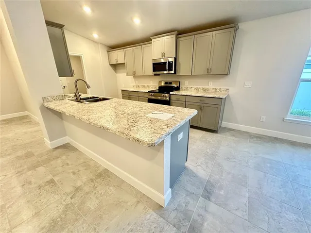 a kitchen with stainless steel appliances a sink a stove a microwave a sink a refrigerator and cabinets