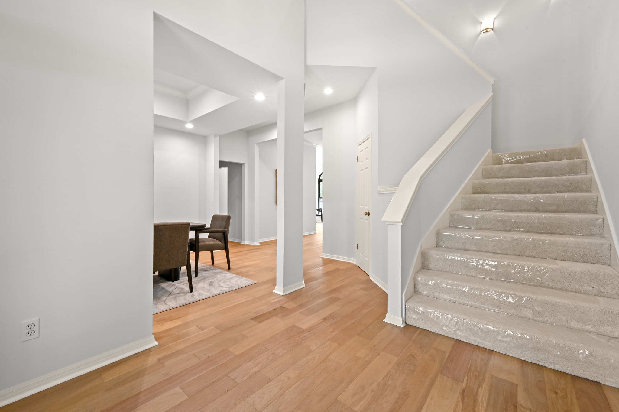 1107 Bowie Road Austin, TX 78733 - Photo 6 of 40 Hardwood flooring in the entry extends towards an inviting dining area, with a carpeted staircase leading to upper levels.