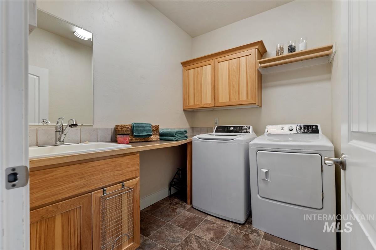 640 Southwest Miner Street Mountain Home, ID 83647 - Photo 13 of 35 Functional laundry area featuring a built-in countertop, wood-finish cabinetry, ceramic tile flooring, a mounted mirror, and a wall-mounted drying rack