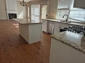 a kitchen with granite countertop a sink a stove and cabinets