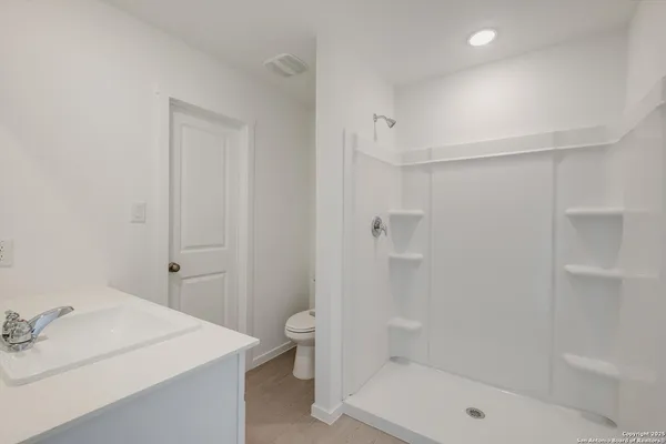 a bathroom with a sink a toilet and shower