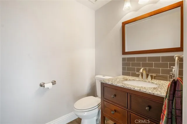 a bathroom with a granite countertop toilet a sink and mirror