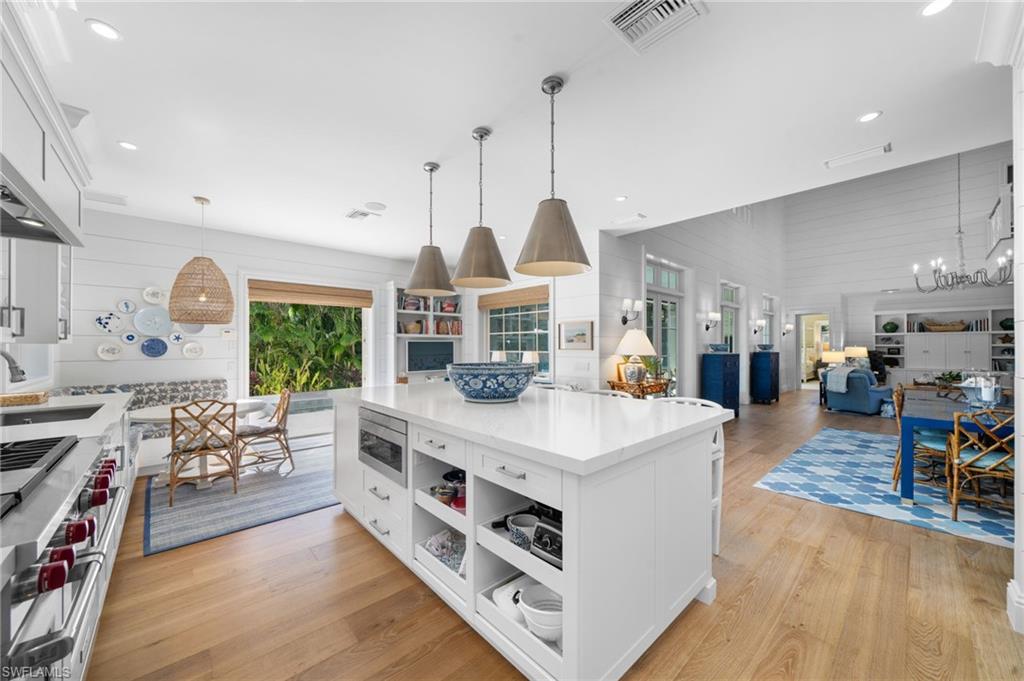 390 Windward Way Naples, FL 34103 - Photo 18 of 42 a large kitchen with stainless steel appliances a stove a sink a dining table and chairs