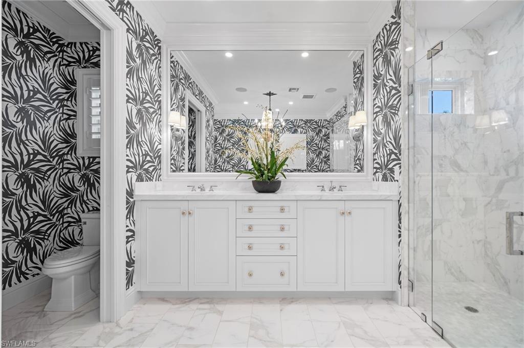 390 Windward Way Naples, FL 34103 - Photo 23 of 42 a bathroom with a bathtub sink vanity mirror and toilet