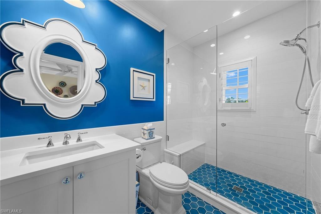 390 Windward Way Naples, FL 34103 - Photo 35 of 42 a bathroom with a sink a toilet and a mirror