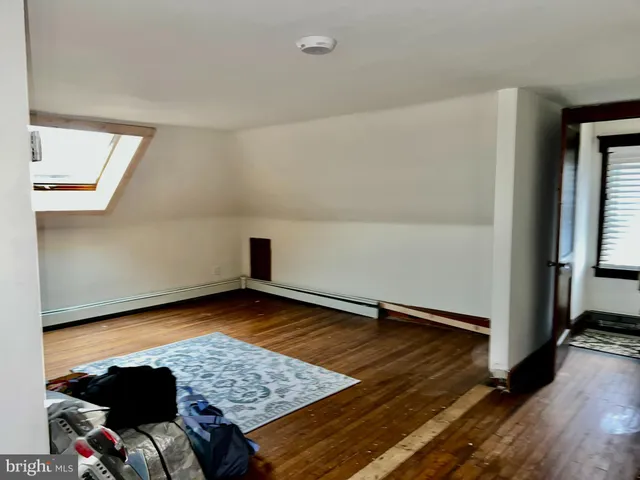 an empty room with wooden floor closet and windows