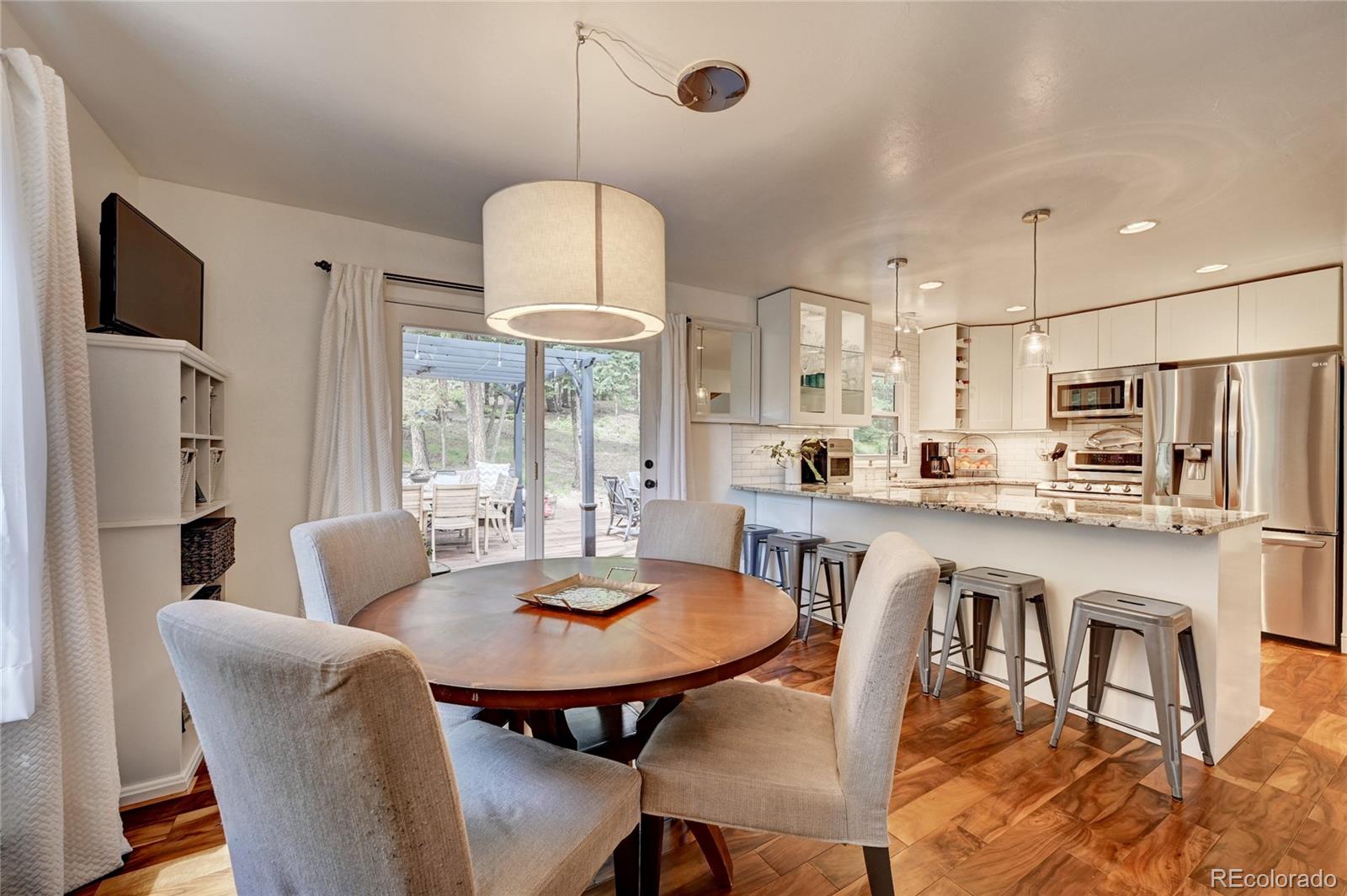 6549 Modoc Lane Evergreen, CO 80439 - Photo 11 of 39 a kitchen with stainless steel appliances a dining table and chairs