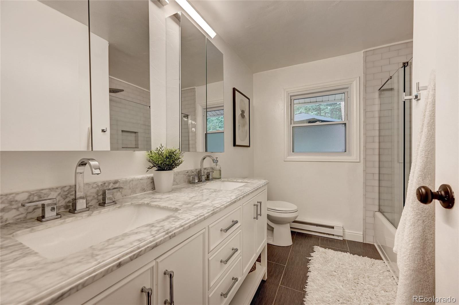 6549 Modoc Lane Evergreen, CO 80439 - Photo 14 of 39 a bathroom with a granite countertop sink toilet and mirror