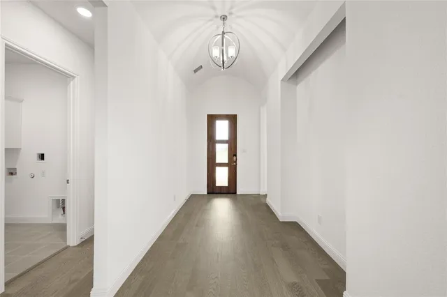 a view of a hallway with wooden floor and a chandelier