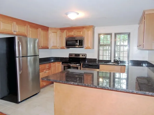 a kitchen with stainless steel appliances granite countertop a refrigerator a stove and a sink with granite countertops