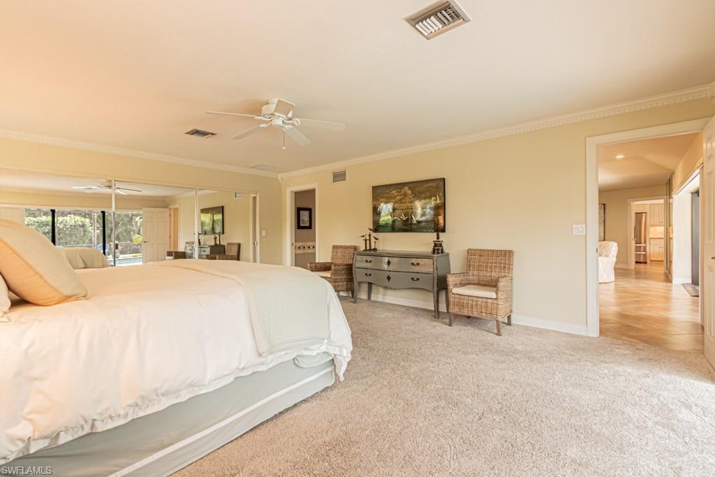 2308 Kings Lake Boulevard Naples, FL 34112 - Photo 19 of 36 a spacious bedroom with a bed a table and chair