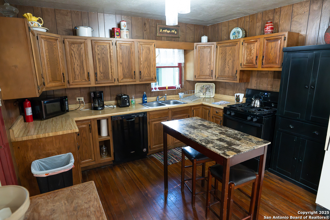35298 Ranch To Market Road 187 Vanderpool, TX 78885 - Photo 19 of 29 a kitchen with a refrigerator a stove a sink dishwasher and wooden cabinets with wooden floor