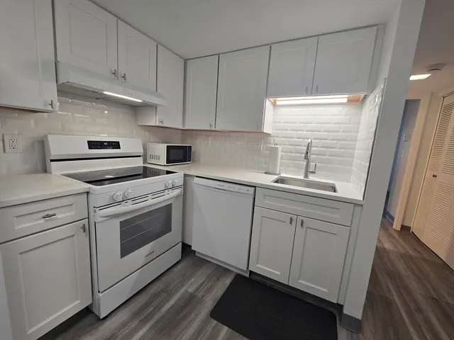 a kitchen with white cabinets stainless steel appliances and sink