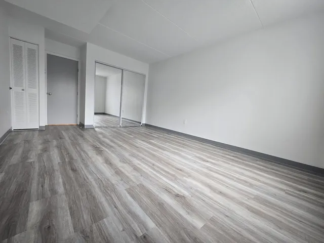 a view of an empty room with wooden floor and closet