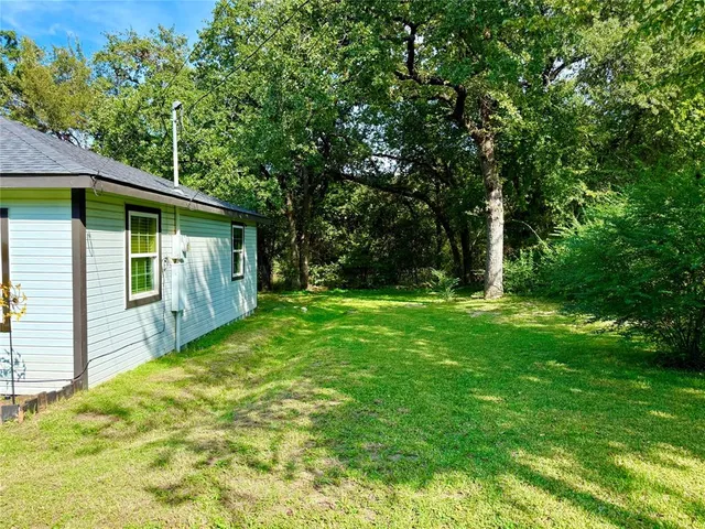 a view of backyard with a barn and large trees
