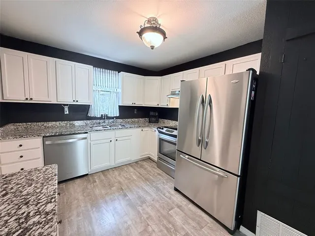 a kitchen with granite countertop white cabinets and white appliances
