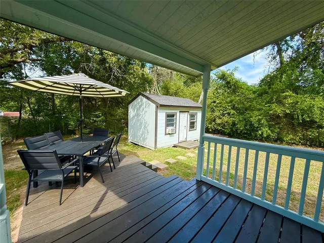 a view of a patio with table and chairs under an umbrella with wooden floor