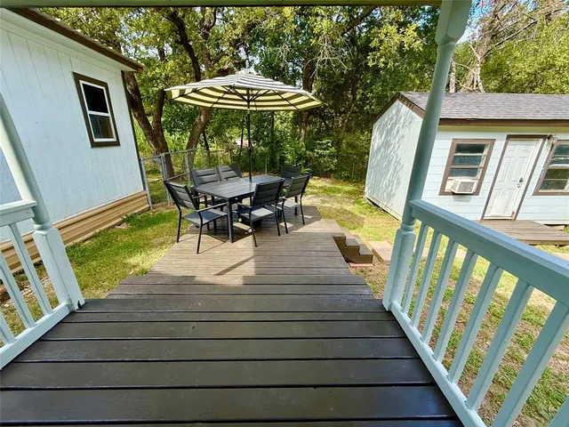 a view of a patio with table and chairs under an umbrella with wooden floor