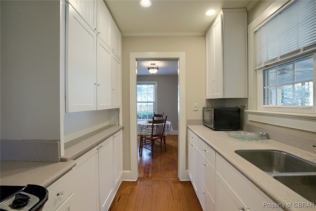 10371 Buckley Hall Road Mathews, VA 23109 - Photo 5 of 28 Kitchen featuring light wood-type flooring, white cabinets, light countertops, and a sink