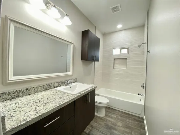 a bathroom with a granite countertop sink a toilet and shower