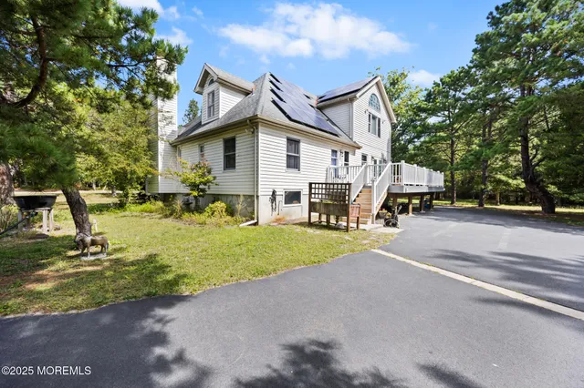 a view of a house with a yard and large trees
