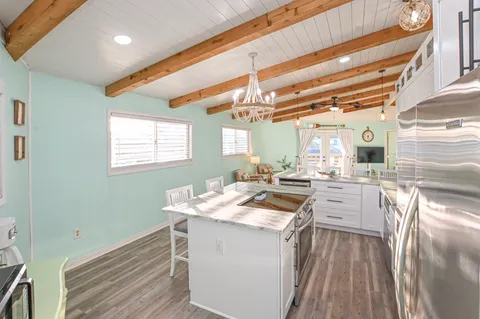 a large white kitchen with a stove a sink and dishwasher wooden cabinets with wooden floor