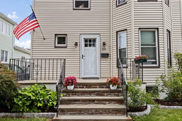 a view of a house with a small yard and potted plants