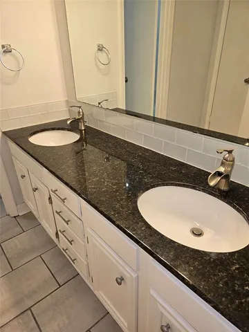 a bathroom with double sink and a mirror