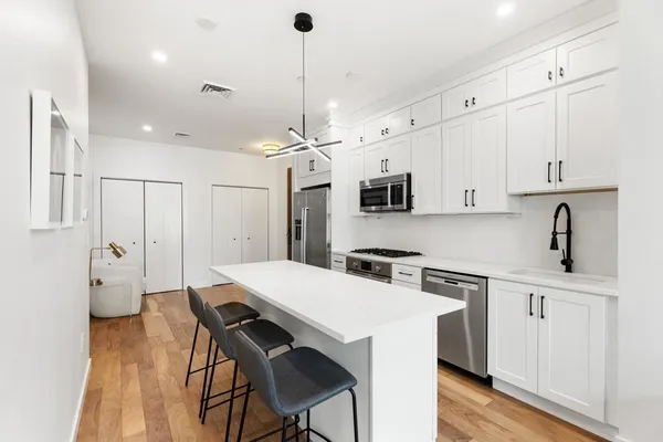 a kitchen with stainless steel appliances a white table chairs refrigerator and cabinets