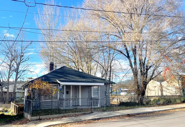 a front view of a house with a yard and large trees