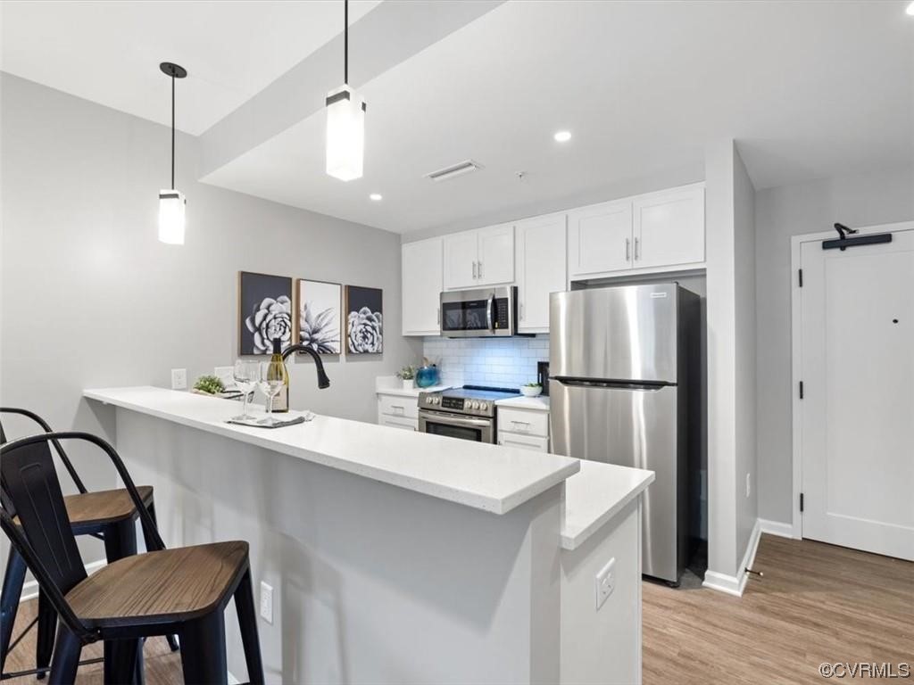 1504 Ewing Park Loop, Unit 207 Midlothian, VA 23113 - Photo 2 of 26 a kitchen with stainless steel appliances a refrigerator a sink a stove a dining table and chairs
