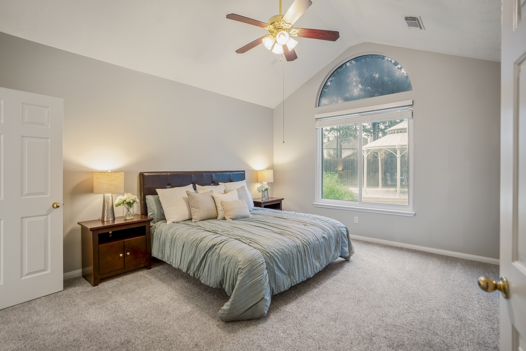 6311 Sparrows Glen Lane Spring, TX 77379 - Photo 17 of 50 Just off the living room, the downstairs primary suite continues the home’s backyard connection with vaulted ceilings and an arched window overlooking the gazebo and yard beyond.