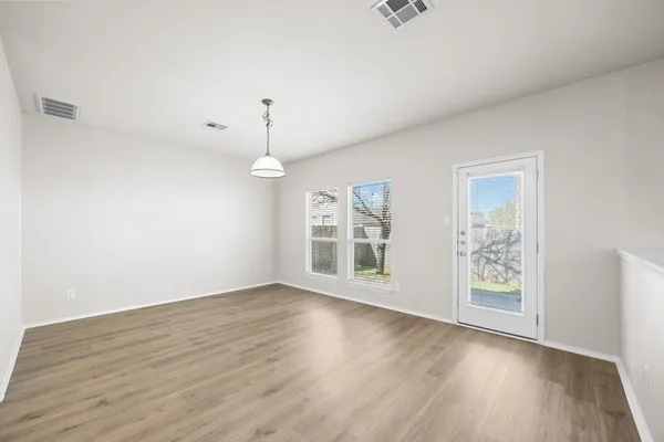 an empty room with wooden floor chandelier fan and windows