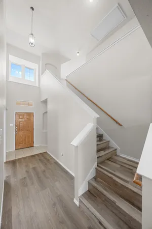 a view of an empty room with wooden floor and stairs