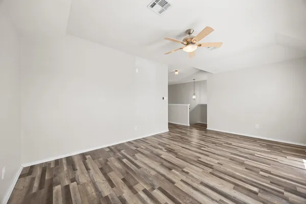 a view of empty room with wooden floor and ceiling fan
