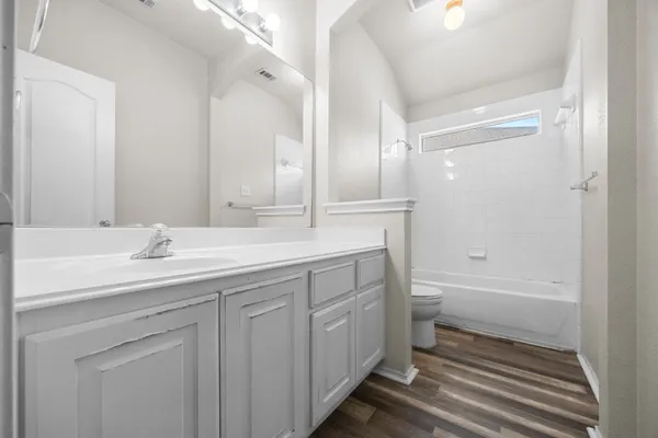 a bathroom with a double vanity sink a toilet and a bathtub