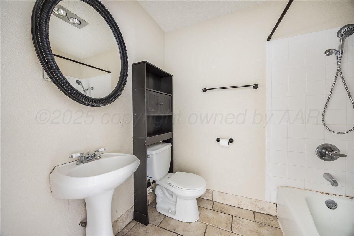 7209 Hatton Road Amarillo, TX 79110 - Photo 10 of 16 a bathroom with a sink a toilet and a mirror