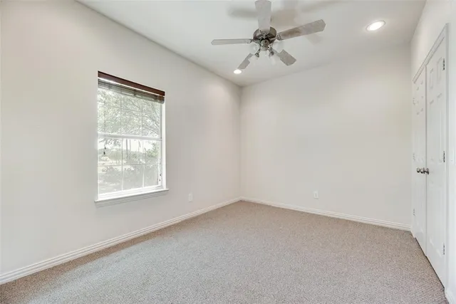 an empty room with a window and a fan