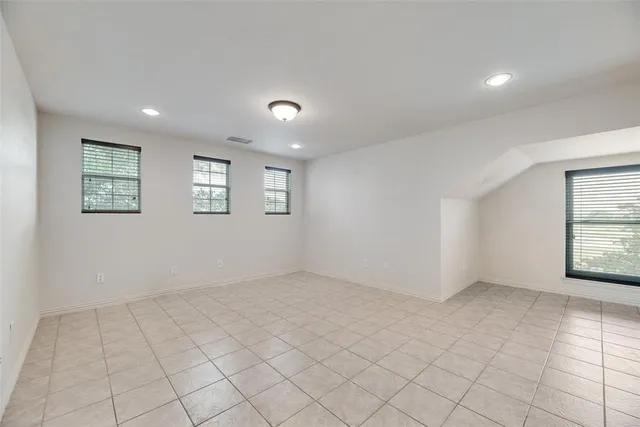 an empty room with windows and chandelier fan