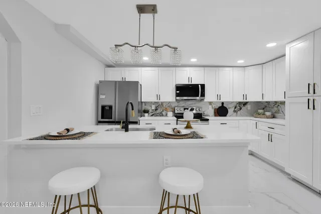 a kitchen with stainless steel appliances a sink a stove a microwave a refrigerator and cabinets