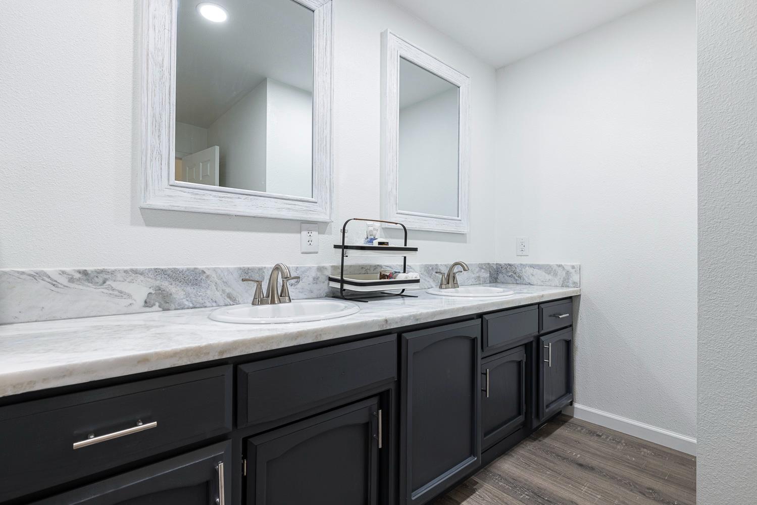 929 Barnett Way Madera, CA 93637 - Photo 18 of 23 a bathroom with a granite countertop sink and a mirror