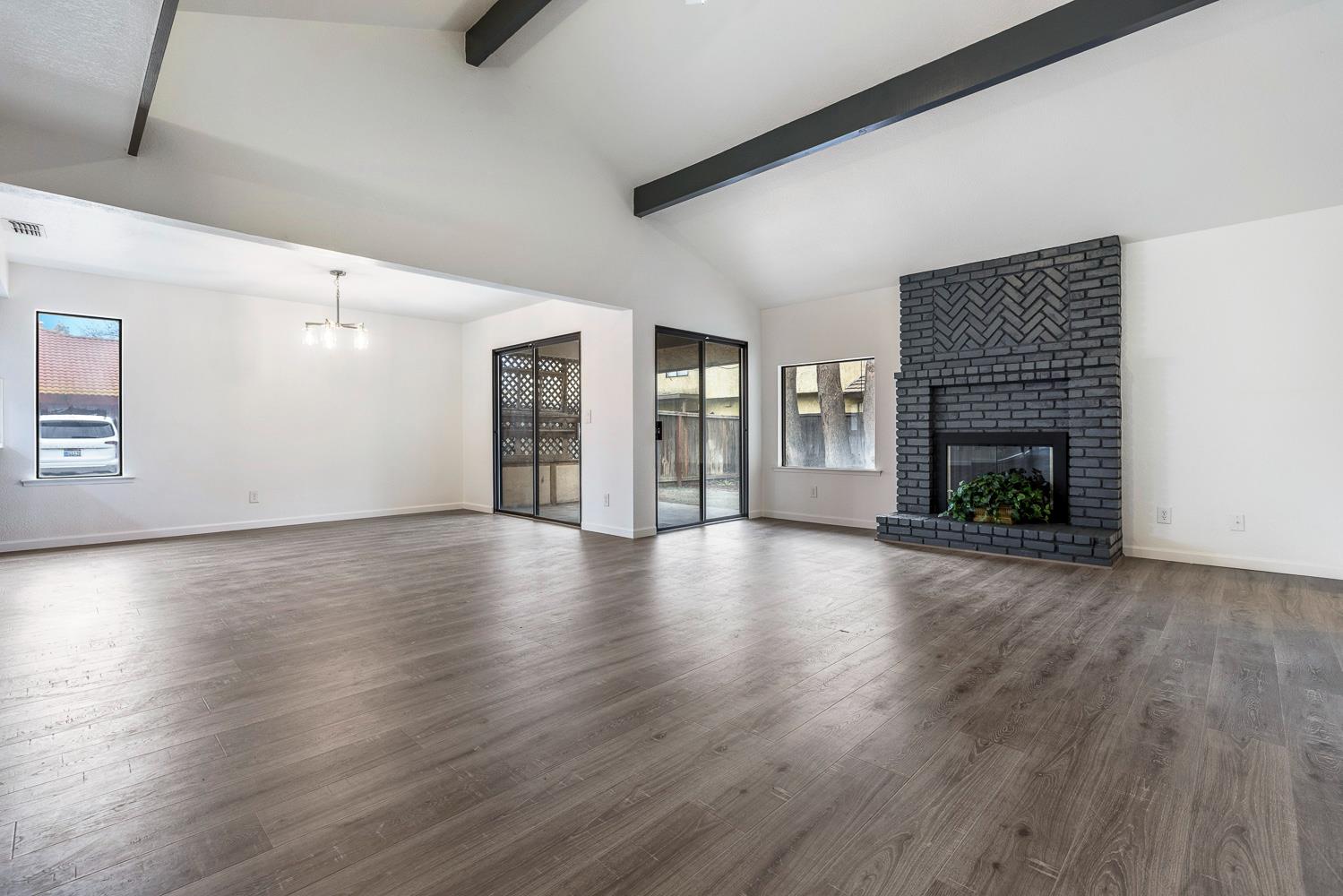 929 Barnett Way Madera, CA 93637 - Photo 5 of 23 an empty room with wooden floor fireplace and windows